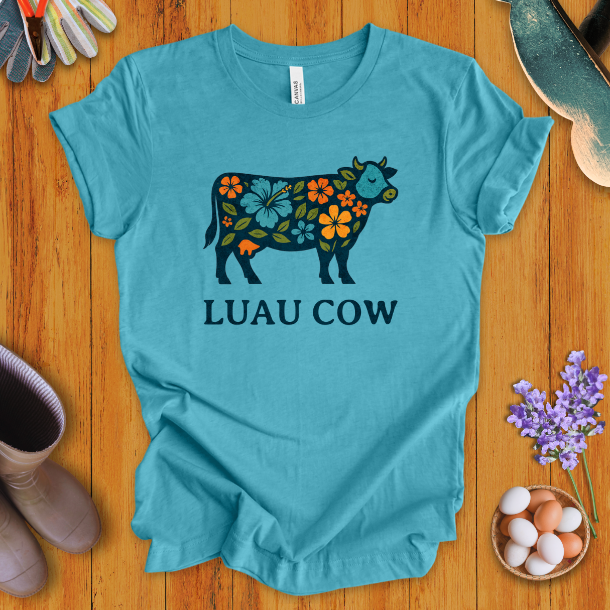 Floral luau cow graphic on heather aqua t-shirt with bold text “LUAU COW”
