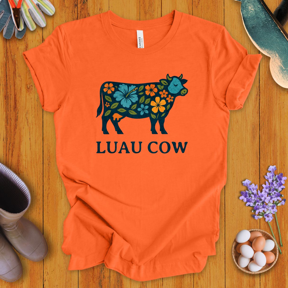 Floral luau cow graphic on orange t-shirt with bold text “LUAU COW”